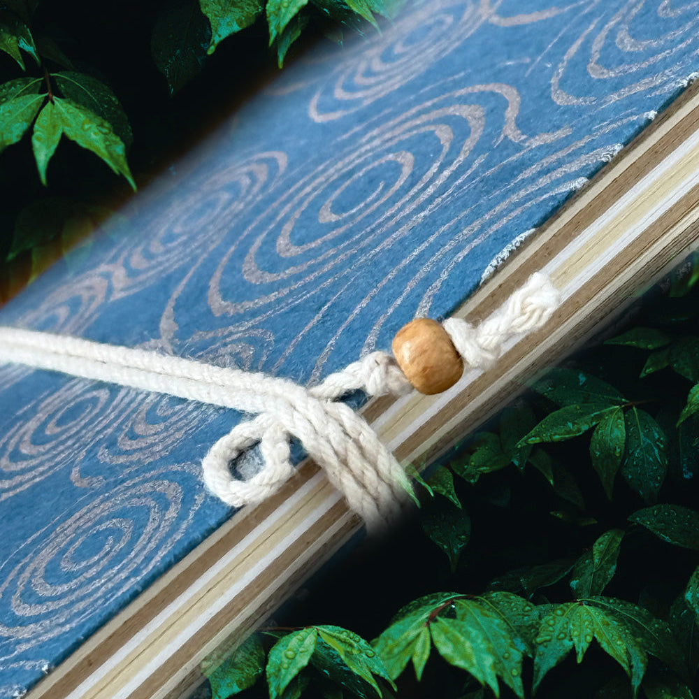 Close Up of Fair Trade Handcrafted Notebook with Blue Fabric Cover with White Swirl Pattern with Twine Binder.