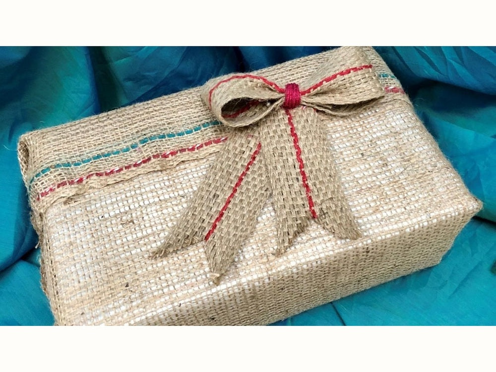 Gift wrapped with compostable materials, including hessian burlap and a jute bow.