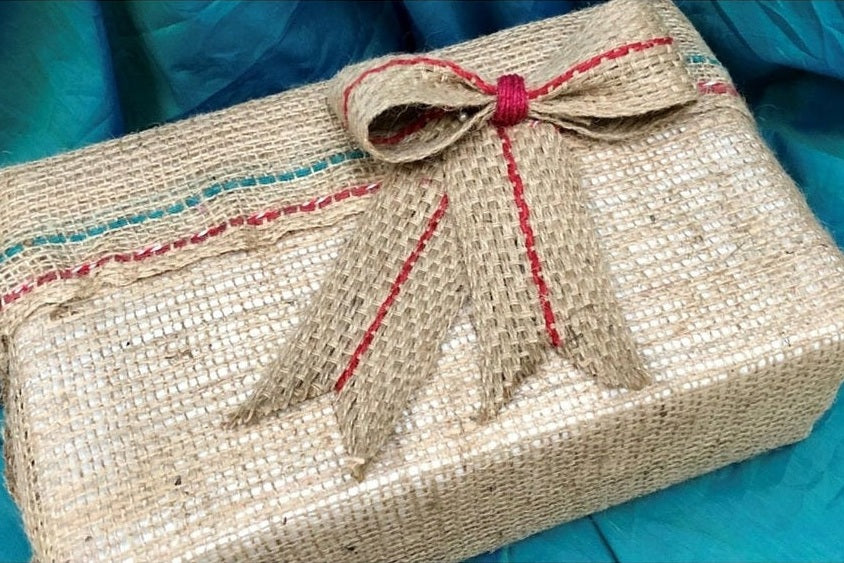 Gift wrapped with compostable materials, including hessian burlap and a jute bow.