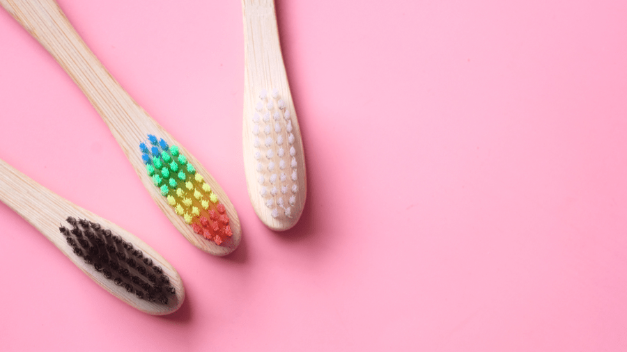 three bamboo toothbrushes on pink background