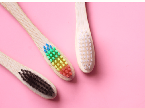 three bamboo toothbrushes on pink background
