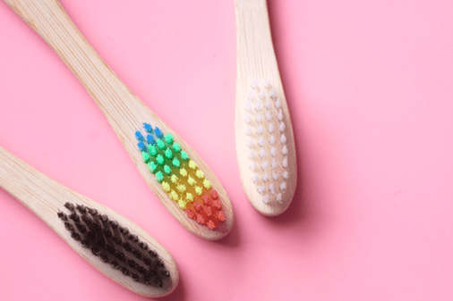 three bamboo toothbrushes on pink background