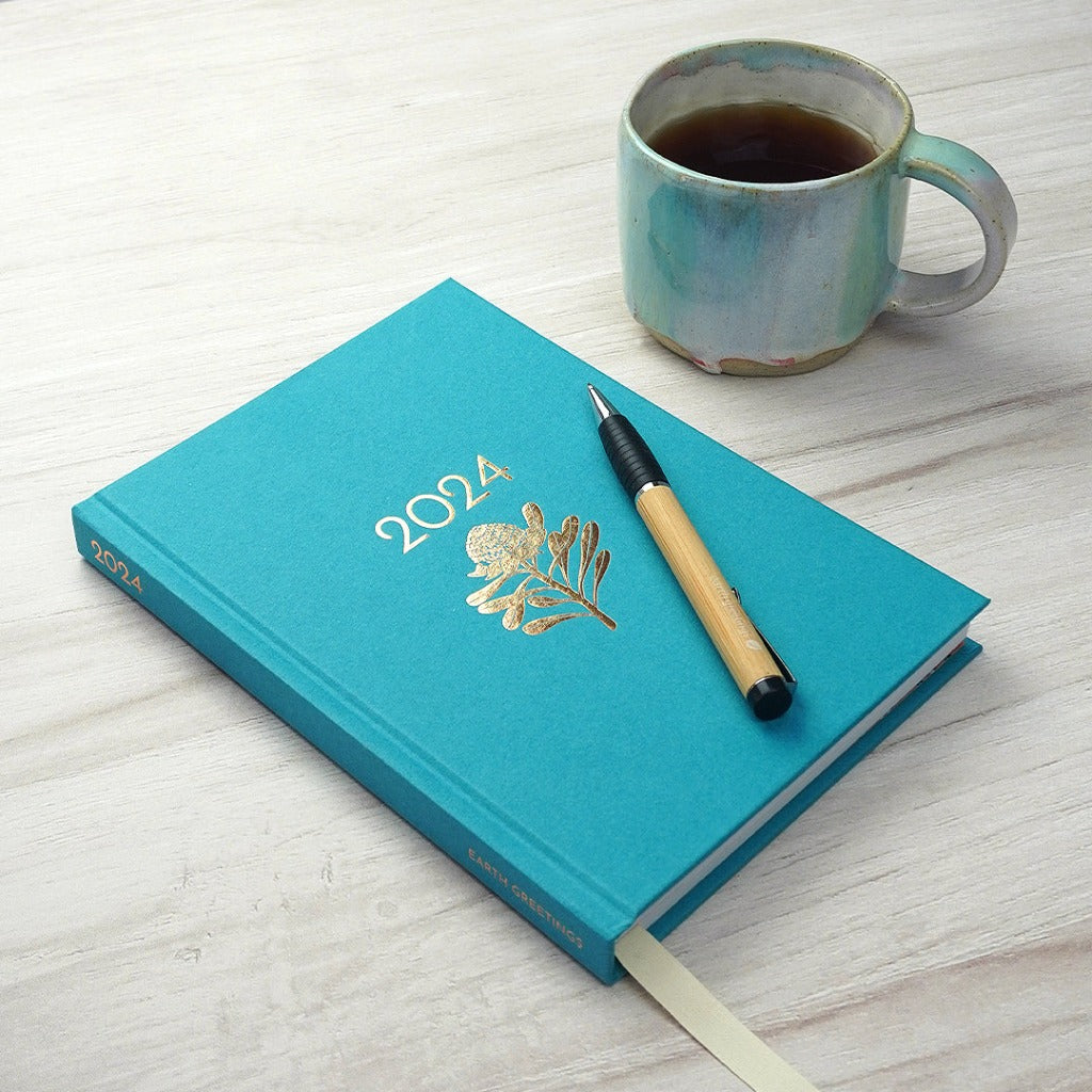 Earth Greetings 2024 Azure Diary with Bamboo Pen and Cup of Coffee.