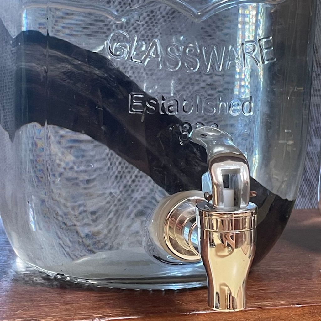 Close up of charcoal water filter stick inside water jar with tap.