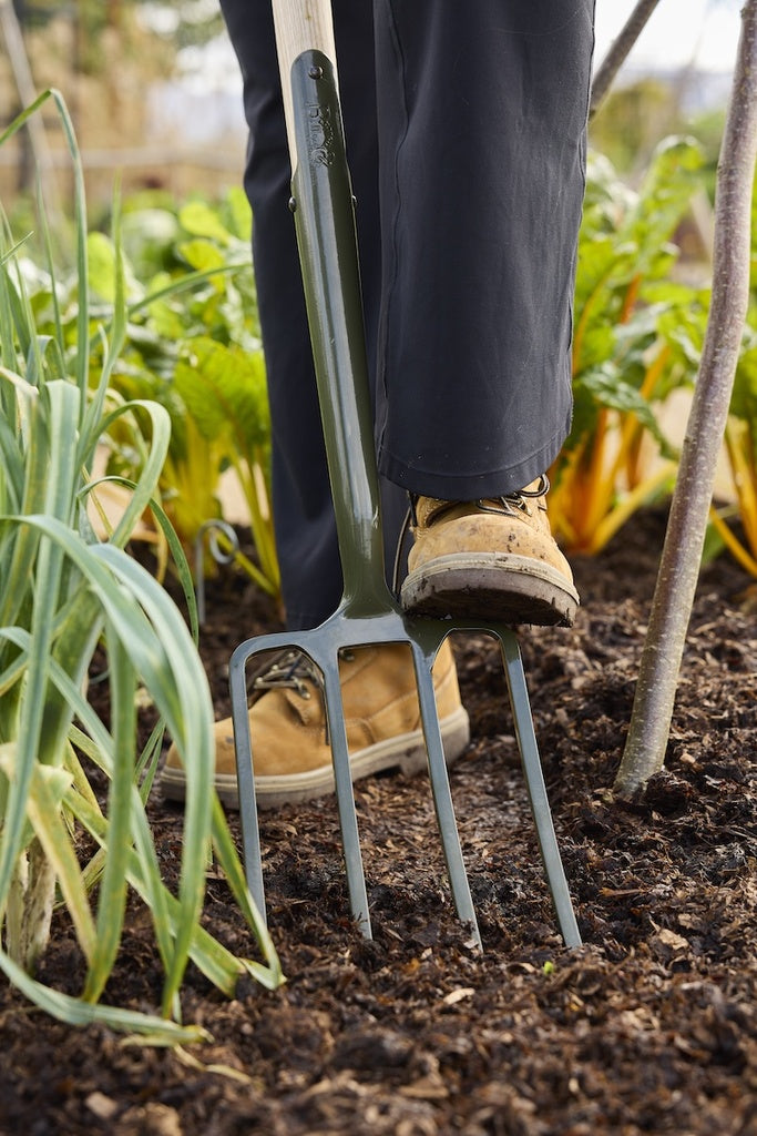 Person gardening with a fork in a garden setting