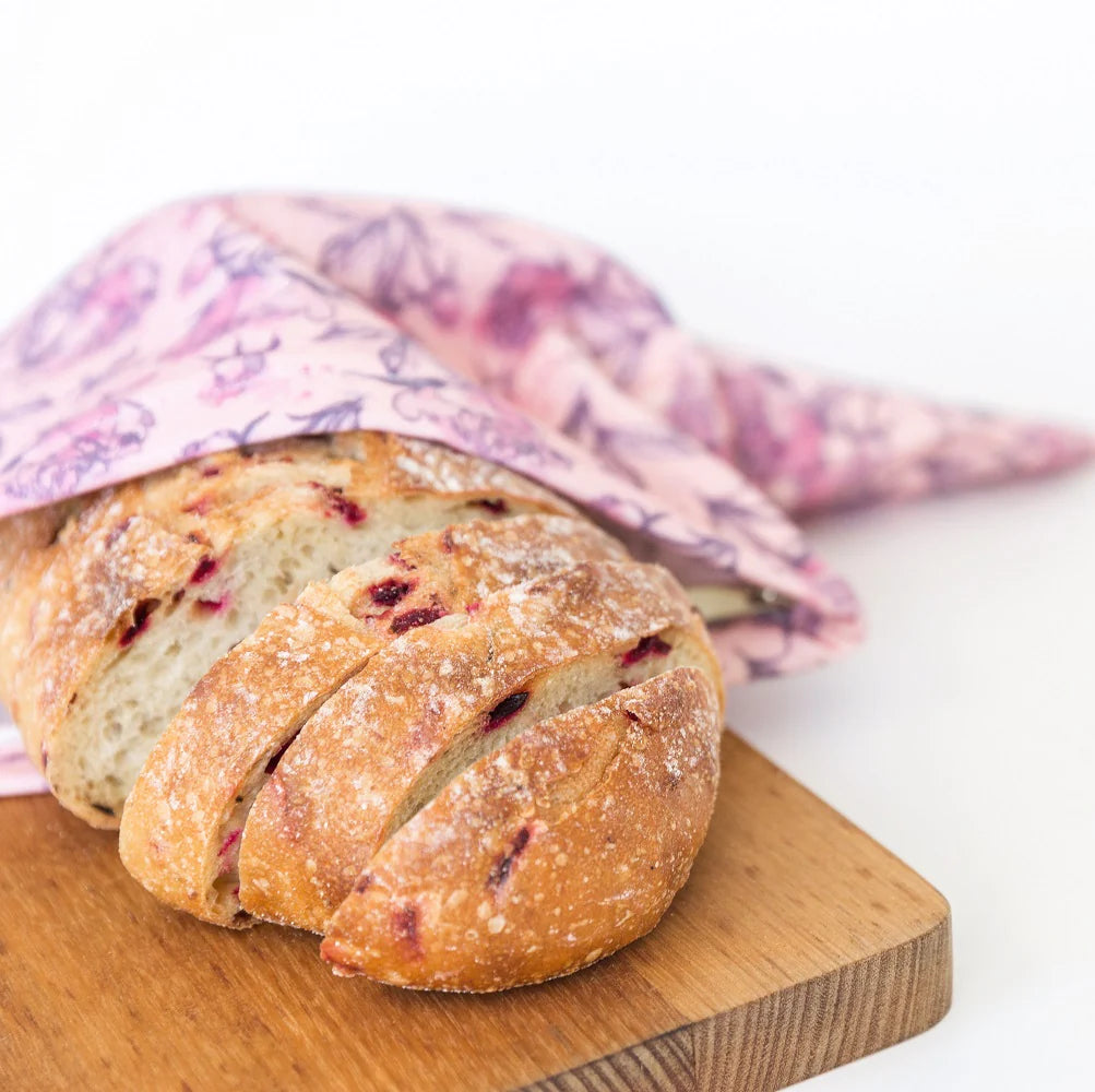 Sliced fruit bread on a wooden cutting board within a Peonies print cotton canvas bread bag