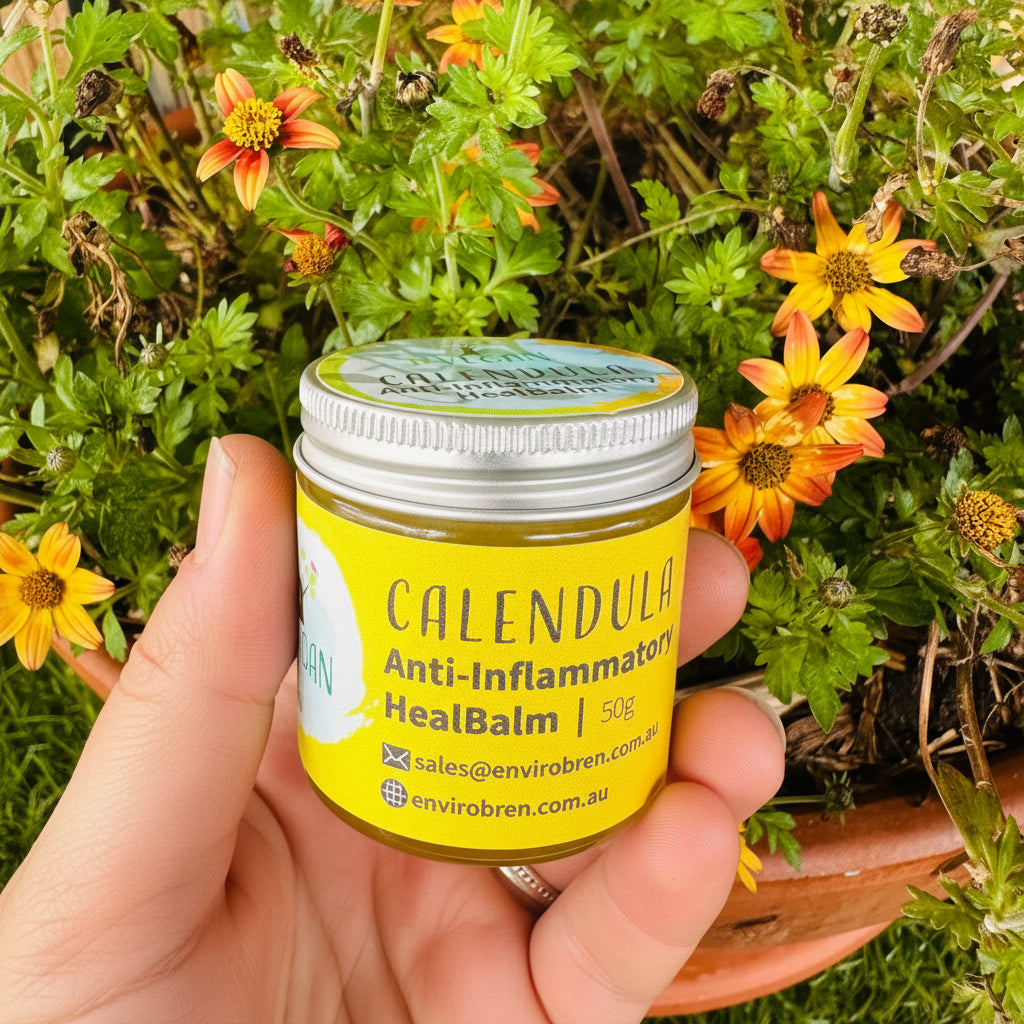Jar of Calendula Anti-Inflammatory Heal Balm by EnviroBren being held in front of Orange Flowers.