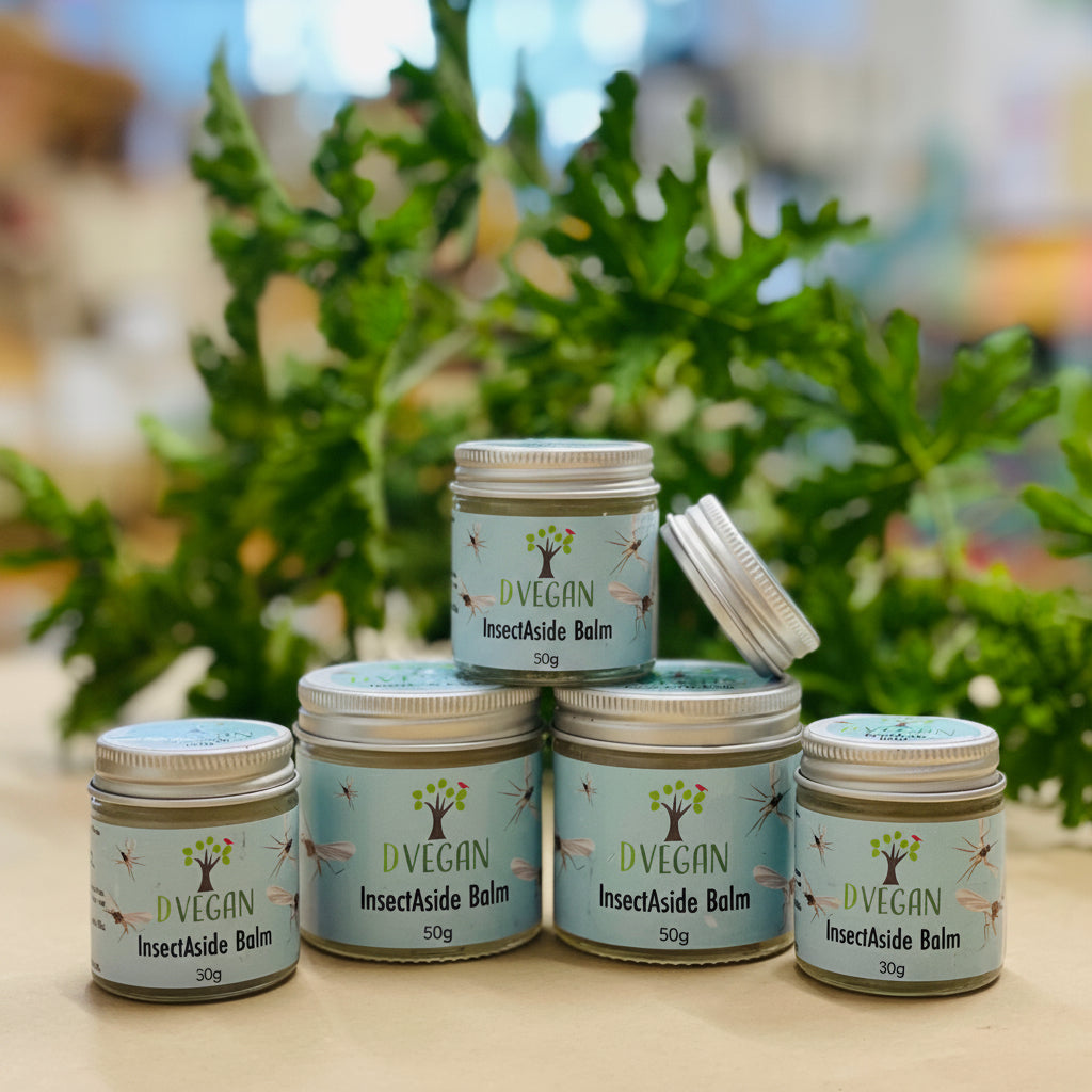 Jars of DVegan InsectAside Balm by EnviroBren in front of Green Leaves. 