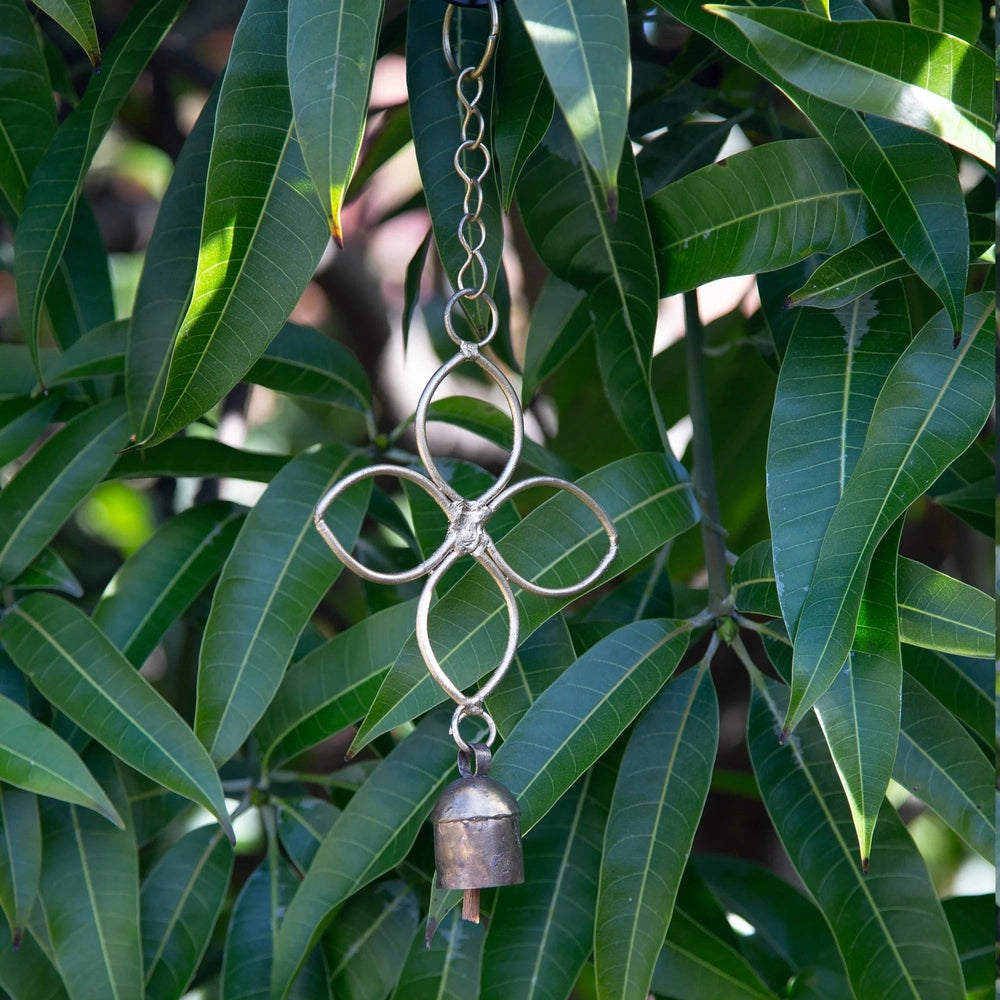 Fair Trade Handmade Decorative Bell Chime with Four Leaf Design against Leafy Backdrop.