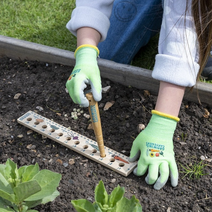 Child planting seeds in a garden bed with gardening gloves on
