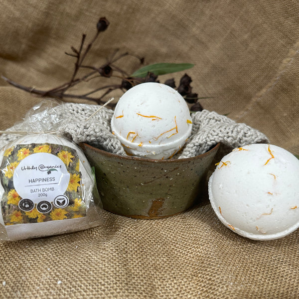 Three Happiness bath bombs, on wrapped with orange flowers and two unwrapped