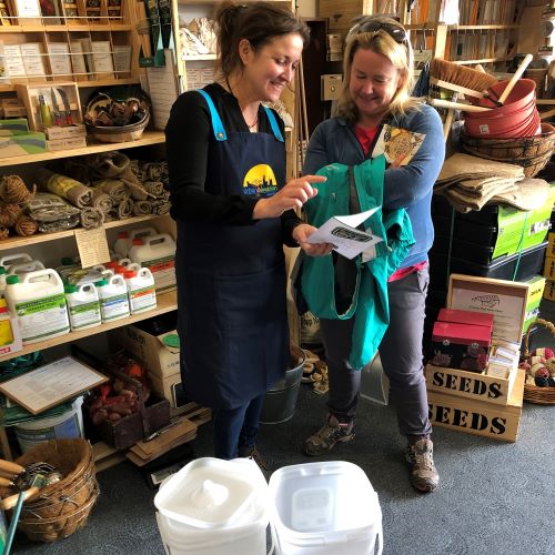 Jo pointing to an instruction booklet, showing a customer how to use a Bokashi compost bin