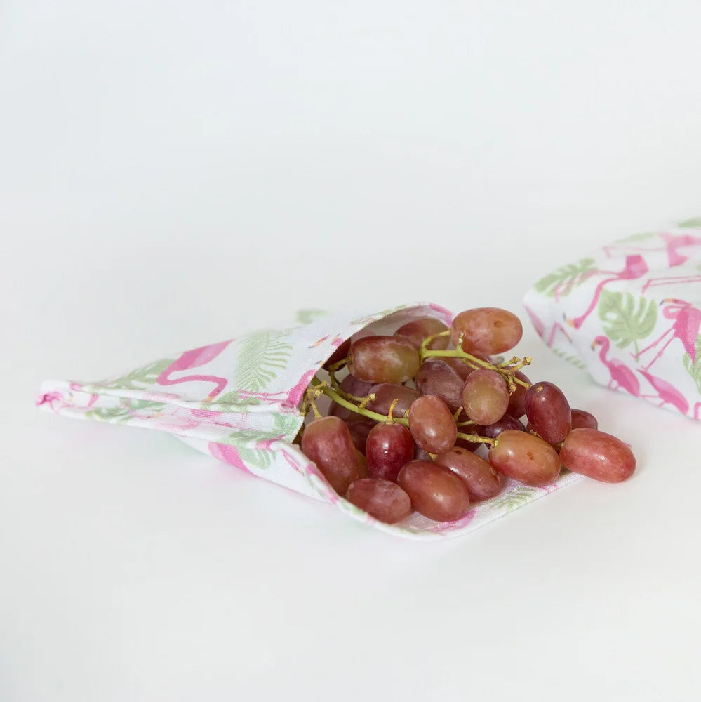 Red grapes in a reusable fabric snack pocket with flamingo design on a white background
