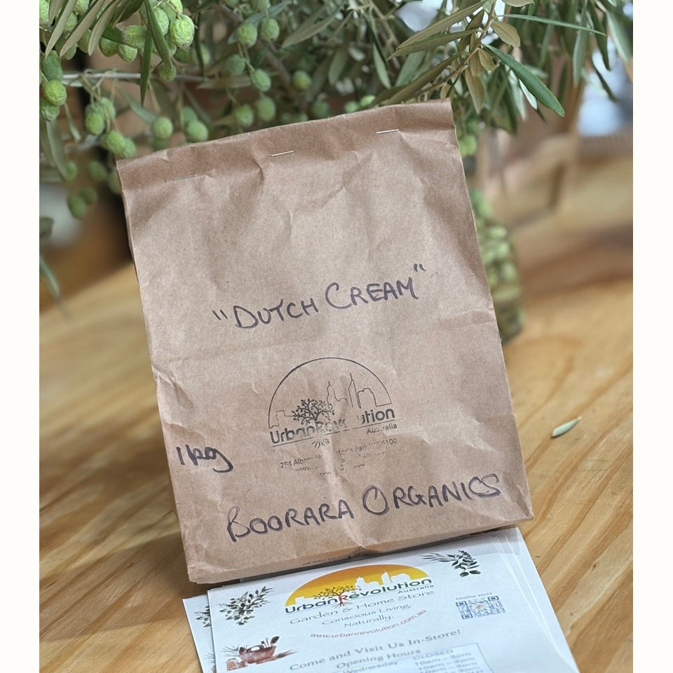 Brown paper bag labeled 'Dutch Cream' from Boorara Organics on a wooden surface with an olive branch in the background.