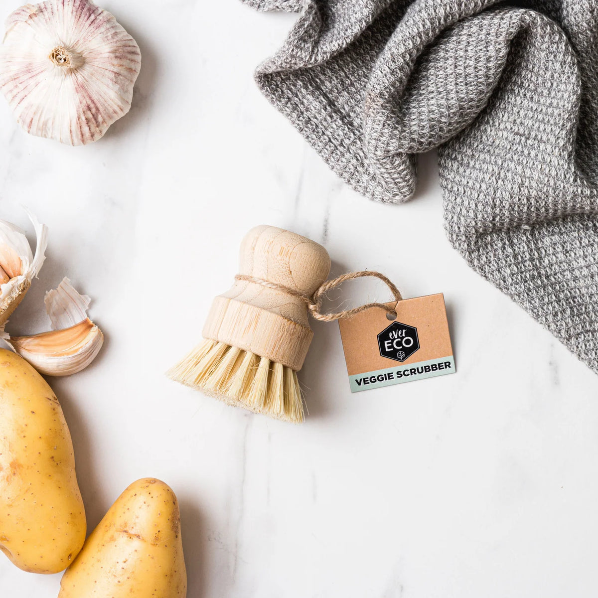 Veggie scrubber brush on bench close to potatoes