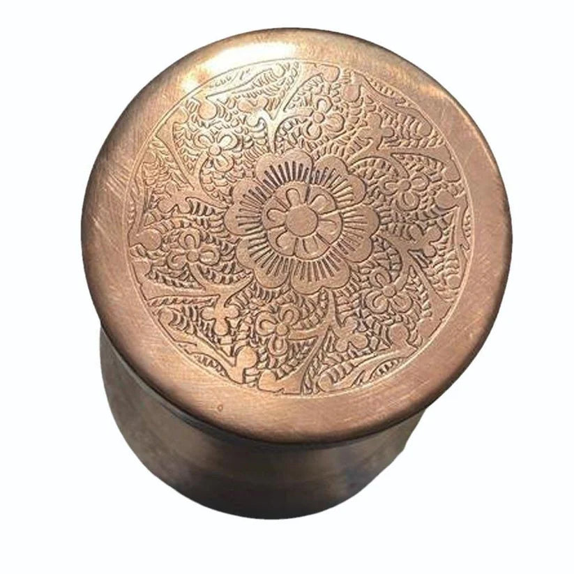 Close up of copper lid for water carafe with intricate hand-carved floral design.