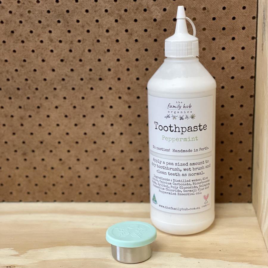 A large bottle of Fluoride Free Peppermint Toothpaste with a small jar