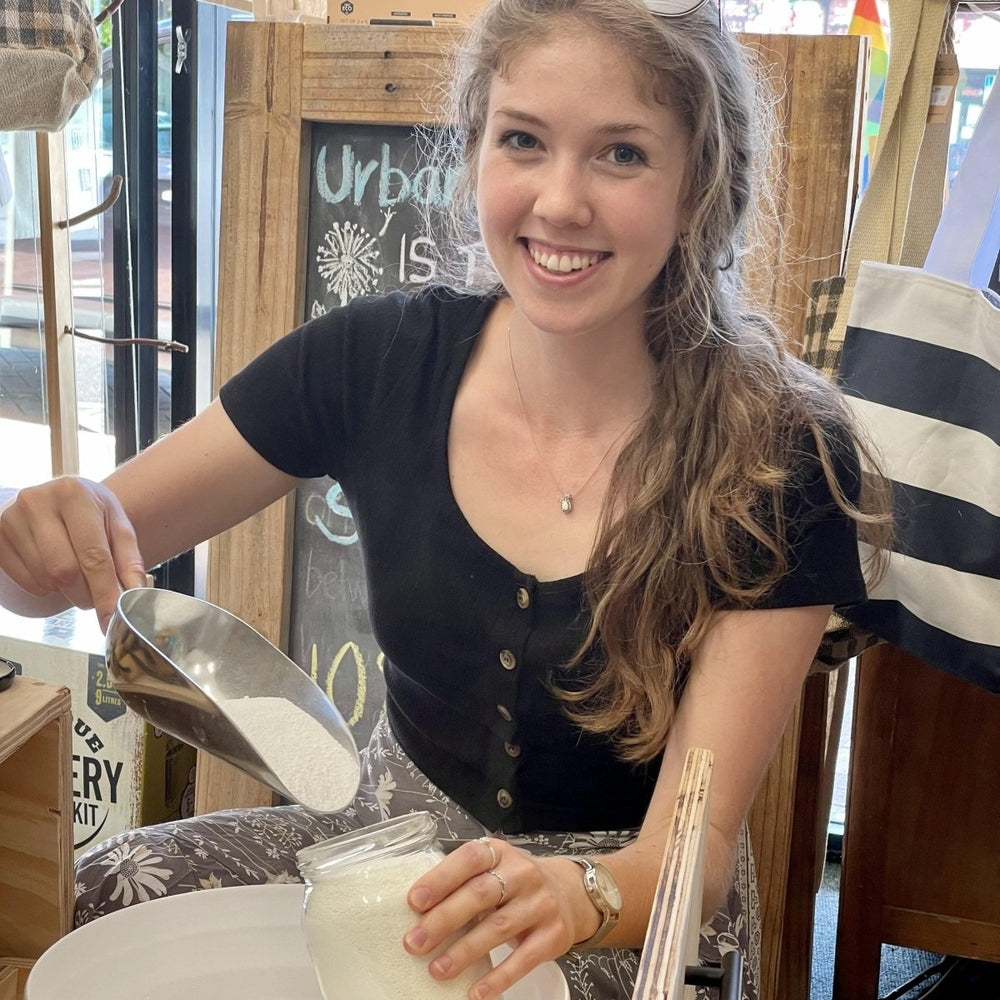 Young woman scooping laundry powder into a jar