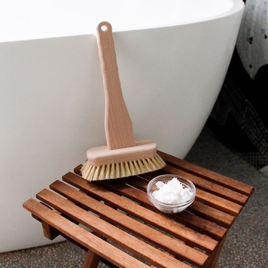 Wooden bath tub brush next to bath
