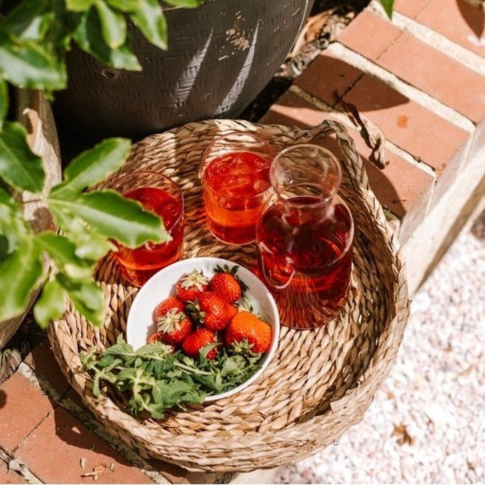 Roogenic tea in glasses with a jug and strawberries in the garden