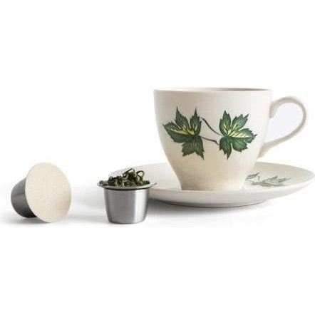 Two Sealpod Reusable Coffee Capsules, One Filled with Tea Leaves, Beside a Tea Cup